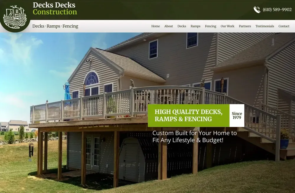 Large elevated wooden deck with white railings attached to a beige two-story house, with a banner advertising decks, ramps